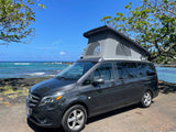 Dark grey pop-top camper van rv rental by Hawaii's coast. Enjoy scenic ocean views & nature adventures.