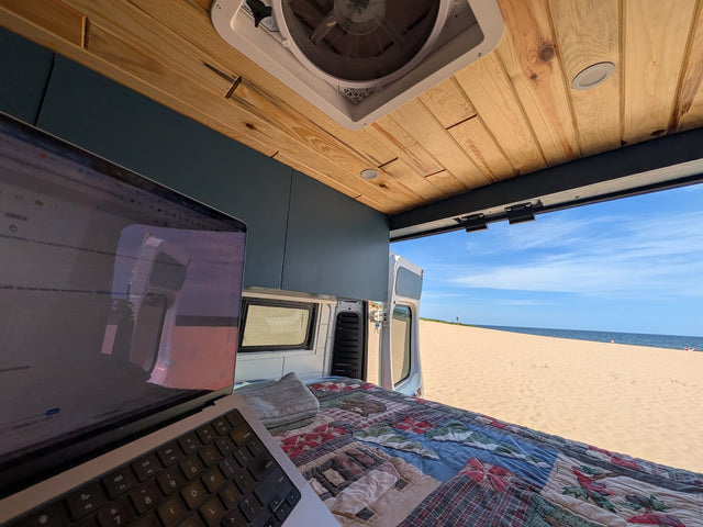 RV rental: Remote work with a view. Laptop on bed inside van