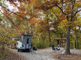 Enjoying an RV rental at a scenic autumn campsite. A pop-up camper, vehicle, and picnic area are nestled among colorful fall trees.