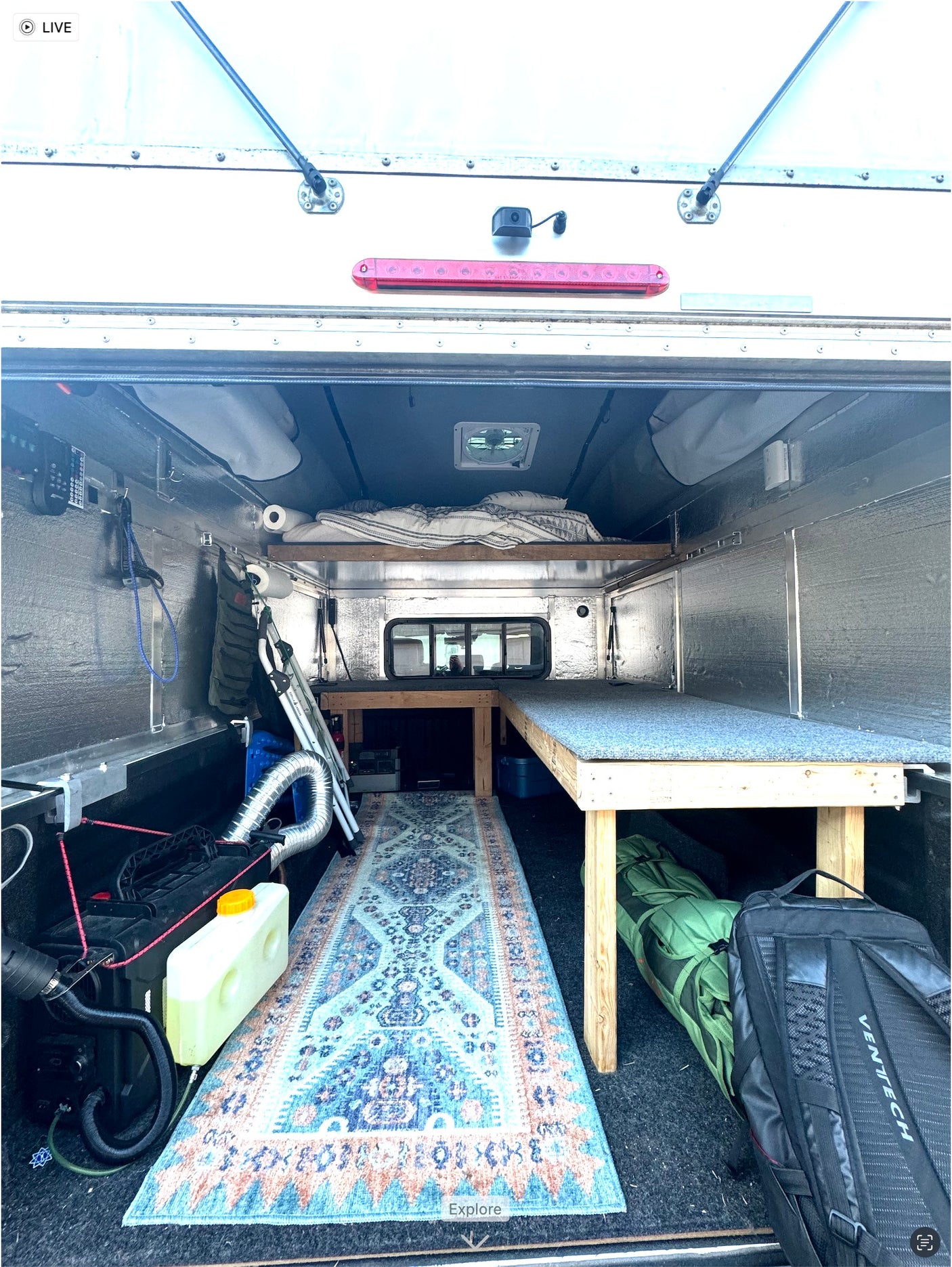 Custom truck camper interior, a perfect RV rental setup. Features bed, bench, diesel heater, and cozy rug.