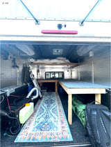 Custom truck camper interior, a perfect RV rental setup. Features bed, bench, diesel heater, and cozy rug.