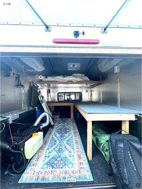 Custom truck camper interior, a perfect RV rental setup. Features bed, bench, diesel heater, and cozy rug.