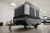 This dark gray and black pop-up travel trailer, a versatile RV rental, is set up and ready for camping adventures.