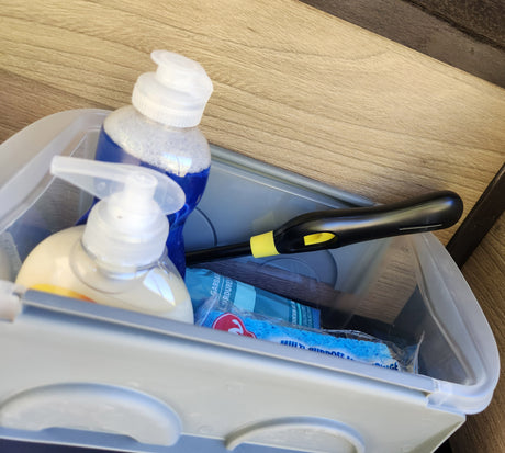 Essential RV rental supplies: soap, lighter, sponge, and garbage bags neatly organized in a handy bin.
