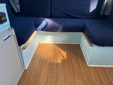 RV rental: Compact interior with blue cushioned seating, wood laminate floor, and a Norcold mini-fridge.