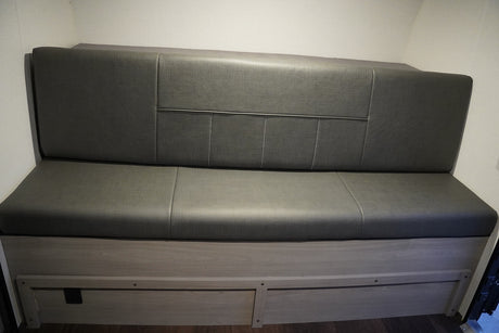 RV rental: Gray upholstered bench seating with storage drawers, ideal for comfortable travel.