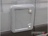 Exterior of an RV rental showing a grey utility access hatch with a lock and hinges for secure storage.