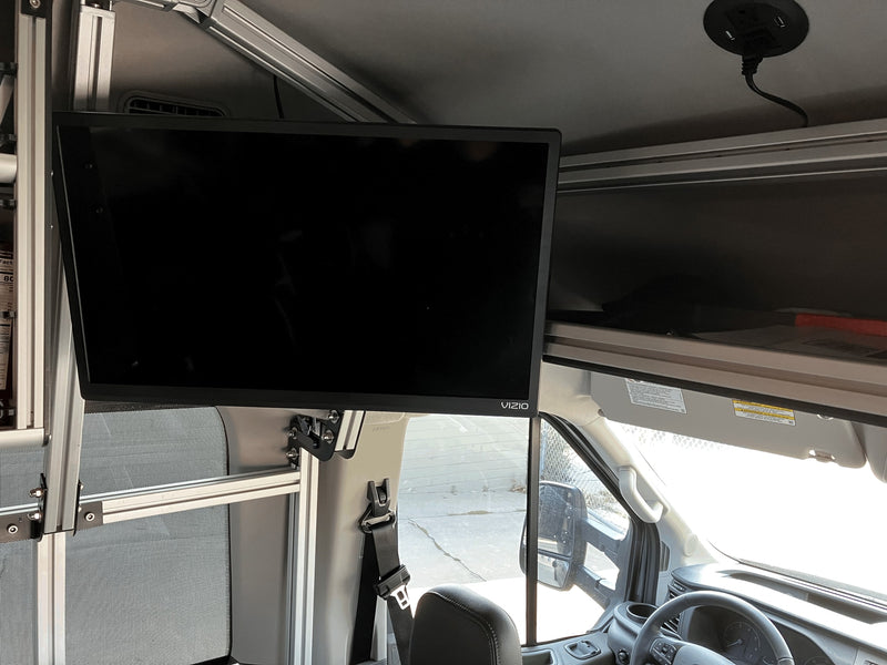 Inside an RV rental, a Vizio TV is mounted on an aluminum frame, beside overhead storage and a ceiling power outlet. — photo 17