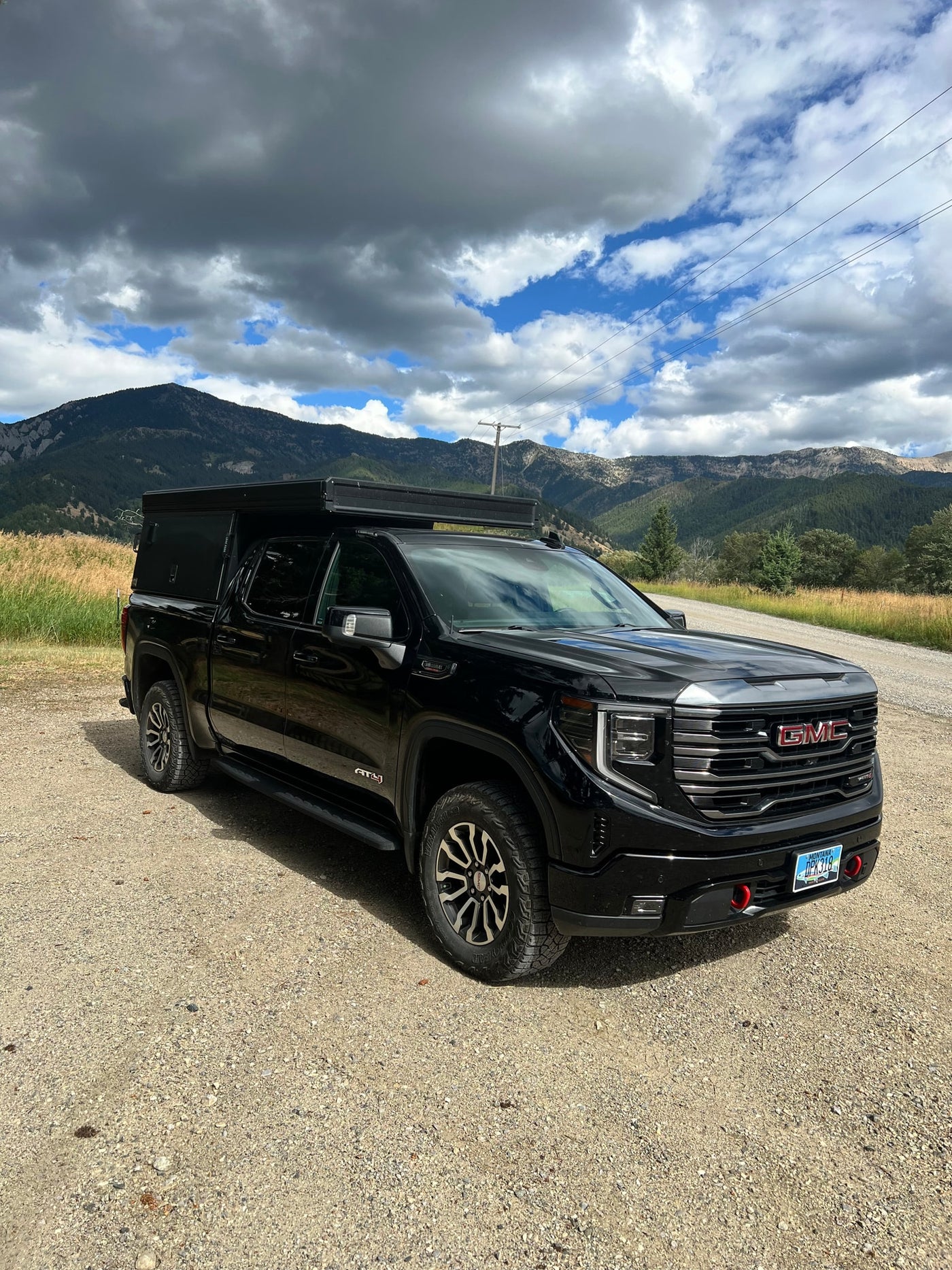 Explore Montana's mountains with this black GMC truck & camper, an ideal RV rental for off-grid adventures under a dynamic sky. — photo 2