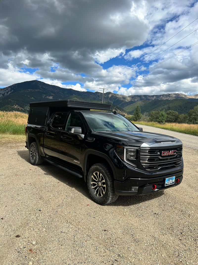 Explore Montana's mountains with this black GMC truck & camper, an ideal RV rental for off-grid adventures under a dynamic sky. — photo 2