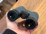 Gray Athlon Midas 8x42 binoculars held in hand, ideal for wildlife viewing on your next rv rental trip or nature exploration.