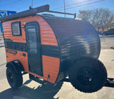 Bright orange and black Sunray Sport teardrop RV rental, ready for your next outdoor adventure.