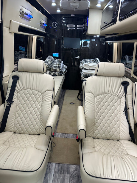 RV rental: Plush cream interior with diamond-quilted seats, convertible beds, and entertainment area for comfort.