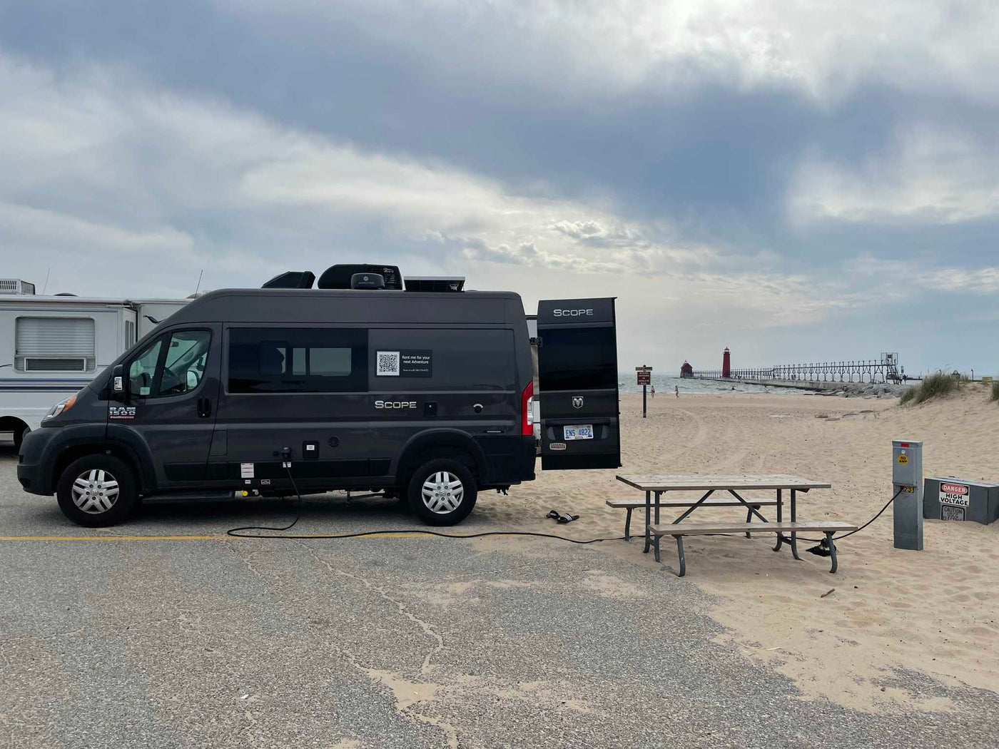 This Scope **RV rental** camper van is perfectly set up at a beach campsite, enjoying electric hookup and lighthouse views. — photo 16
