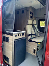 Step inside this RV rental featuring a sleek kitchenette with fridge and cozy, quilted passenger seating. Ideal for travel.