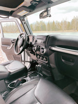 Jeep Wrangler interior, open door to a scenic lake & forest. Perfect for an RV rental adventure to explore nature.