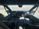 Spacious RV rental interior showing the Mercedes-Benz van's cockpit, dashboard, and black leather driver and passenger seats.