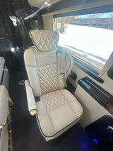 Luxurious RV rental interior featuring a cream quilted captain's chair with black piping and a snowy view outside.