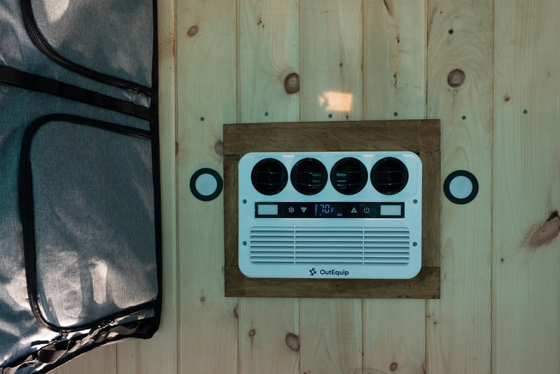 RV rental interior: White AC unit with 70F digital display on wood paneling, next to a grey zippered fabric item. — photo 9