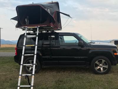 Black Jeep Patriot SUV with a deployed rooftop tent and ladder