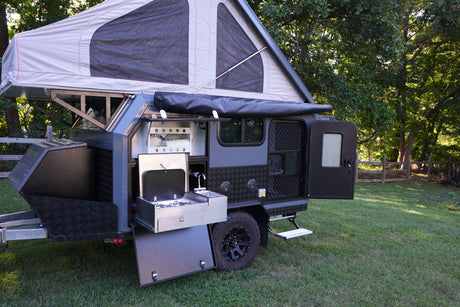 This open rv rental pop-up camper trailer features a full outdoor kitchen with stove, sink, and storage, ready for adventure.