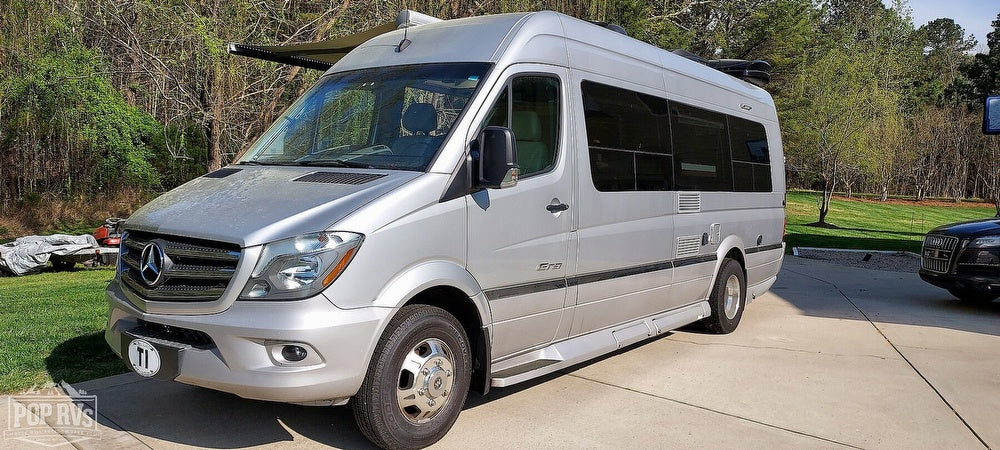 A sleek silver Mercedes Sprinter camper van, ideal for rv rental, is parked outdoors on a sunny day.