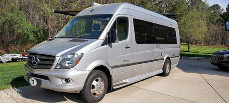 A sleek silver Mercedes Sprinter camper van, ideal for rv rental, is parked outdoors on a sunny day.
