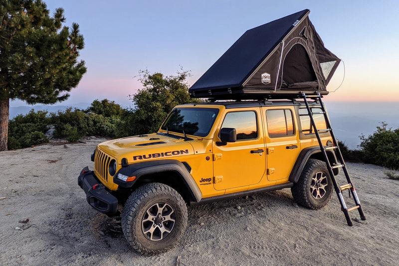 Yellow Jeep Rubicon with a rooftop tent at sunset. Ideal rv rental for scenic overlanding and camping.|Bright yellow Jeep Rubicon with rooftop tent on a dirt road. Explore off-road camping with this adventure RV rental.|Yellow Jeep Wrangler with an open rooftop tent — photo 1
