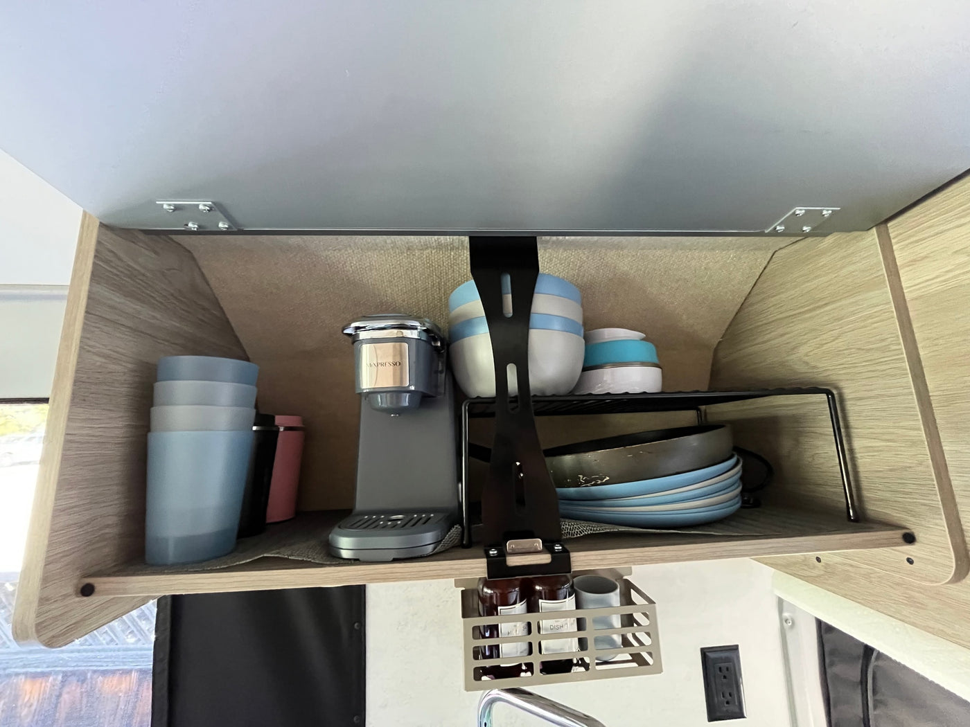 RV rental: Neatly organized overhead kitchen cabinet featuring a Minpresso coffee maker, dishes, and hanging storage. — photo 14