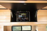 RV rental: Tablet playing "His & Hers" series, mounted in an open wooden overhead cabinet for entertainment.