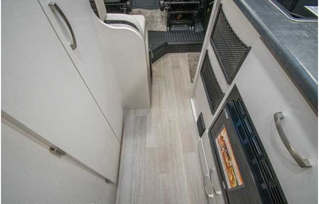 RV rental: Interior view of a galley/hallway with light flooring, cabinets, and a built-in microwave. Compact and functional.