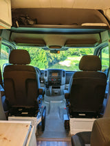 RV rental camper van interior looking forward, revealing the dashboard and a serene waterfront view through the windshield.