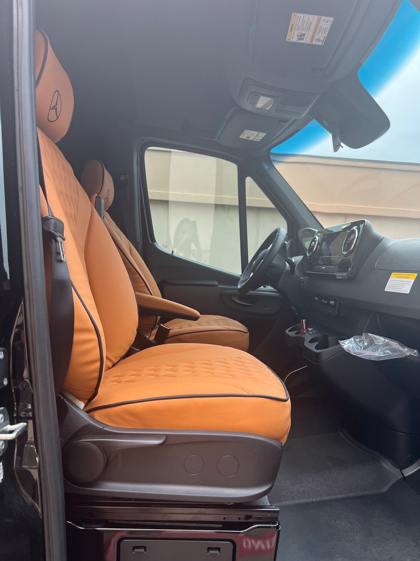 Detailed view of an rv rental van's interior. Highlights tan seats with Mercedes-Benz logo, dashboard, and steering wheel.
