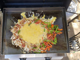 Griddle cooking a delicious RV rental breakfast with eggs, onions, bell peppers, and bacon.