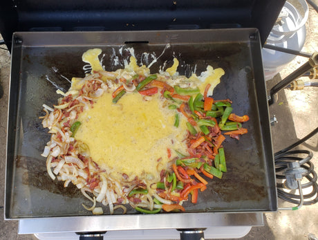 Griddle cooking a delicious RV rental breakfast with eggs, onions, bell peppers, and bacon.