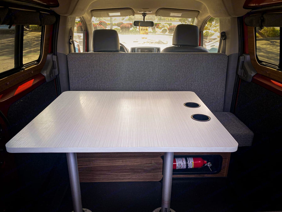 Cozy RV rental interior: A dining table, bench seat, and fire extinguisher are ready for your safe road trip adventure.