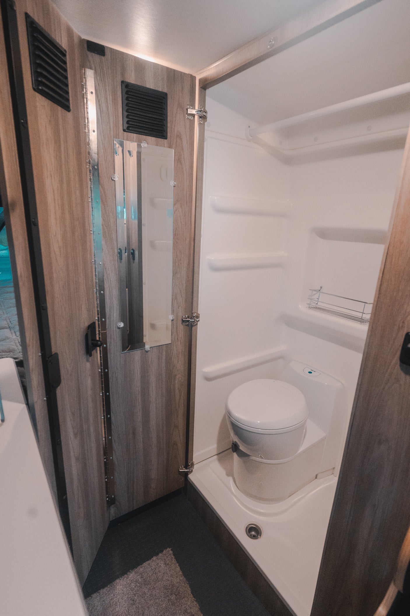 **RV rental** compact bathroom features a toilet, shower stall, and mirrored door, optimizing space for travel.