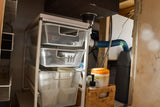 Efficient under-sink storage in an RV rental, featuring pull-out mesh baskets, plumbing, and a grey water tank for compact living.