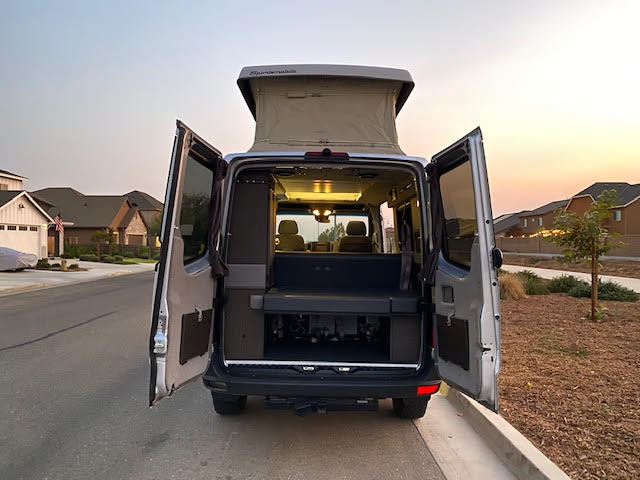  parked on a street at sunset.|A silver RV rental van in a snowy parking lot — photo 3