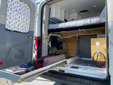 Explore this efficient RV rental: rear storage with pull-out drawer, comfortable bed, and outdoor shower setup.
