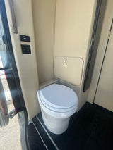 Compact RV rental lavatory with Dometic toilet & wall controls. Clean and functional interior for your travel needs.