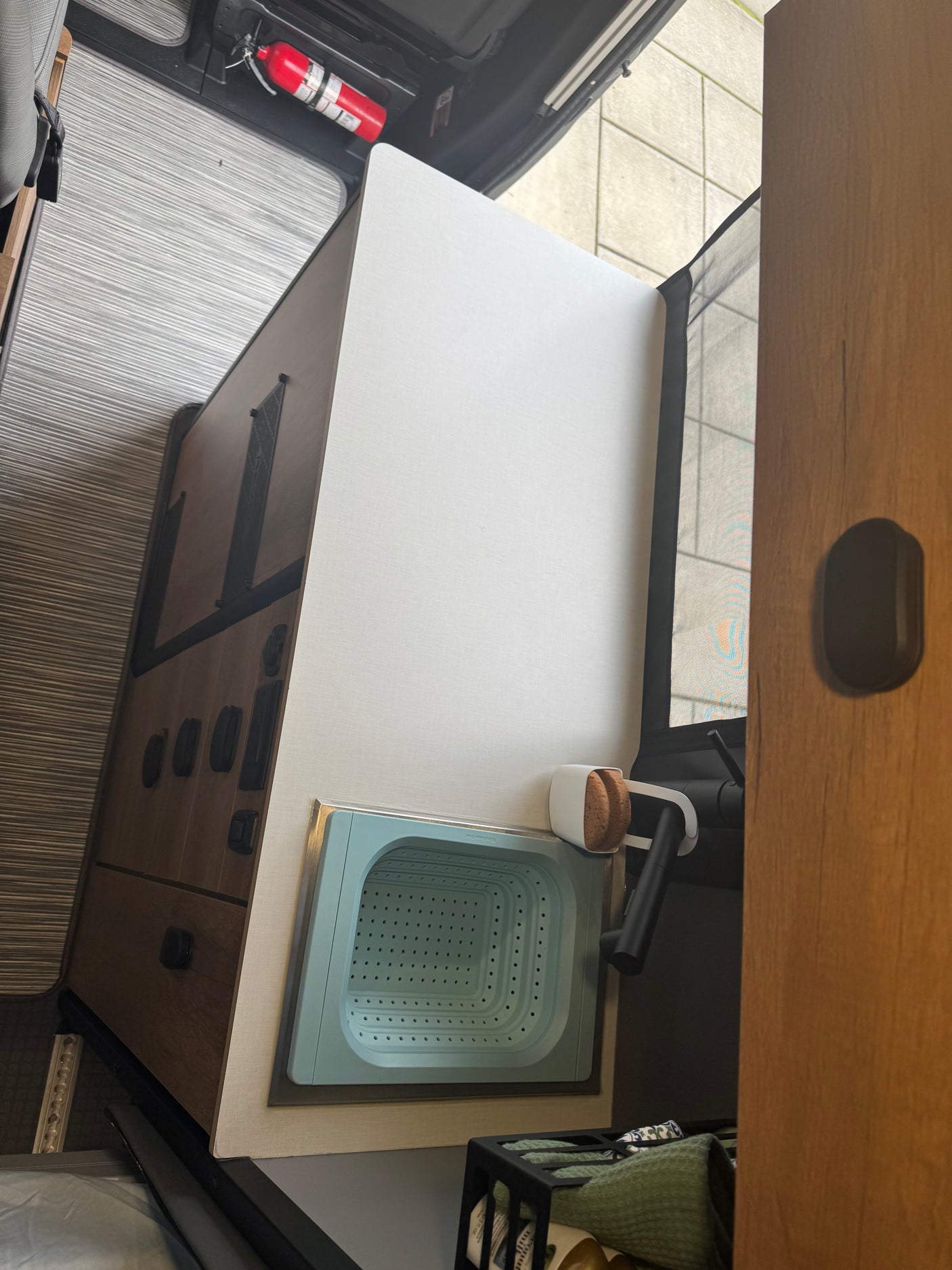 Inside an rv rental: compact kitchen with collapsible sink, fire extinguisher, and smart storage solutions.