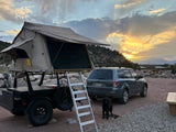 This RV rental adventure includes a rooftop tent, Subaru, and black dog, enjoying sunset at a mountain campsite.