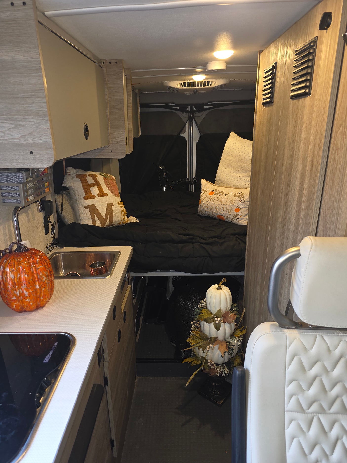 Inviting rv rental interior with a kitchen, sleeping area, and storage. Fall decor adds warmth to this compact living space.