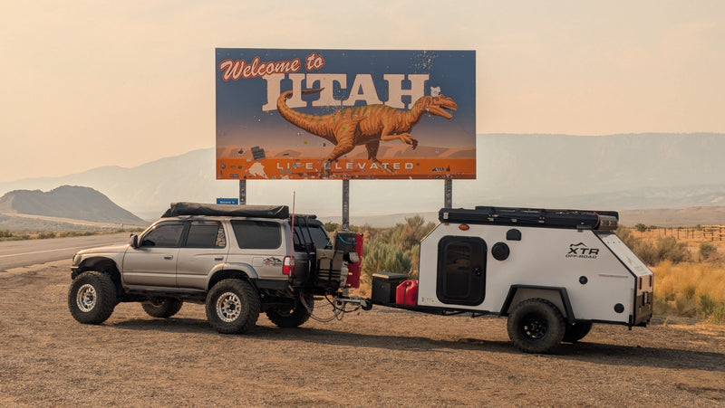 Adventure-ready SUV towing an RV rental camper at Utah's dinosaur welcome sign. — photo 18