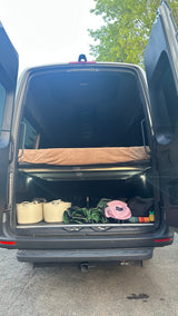 RV rental camper van's open rear reveals a raised bed, starlight headliner, and organized storage space below.
