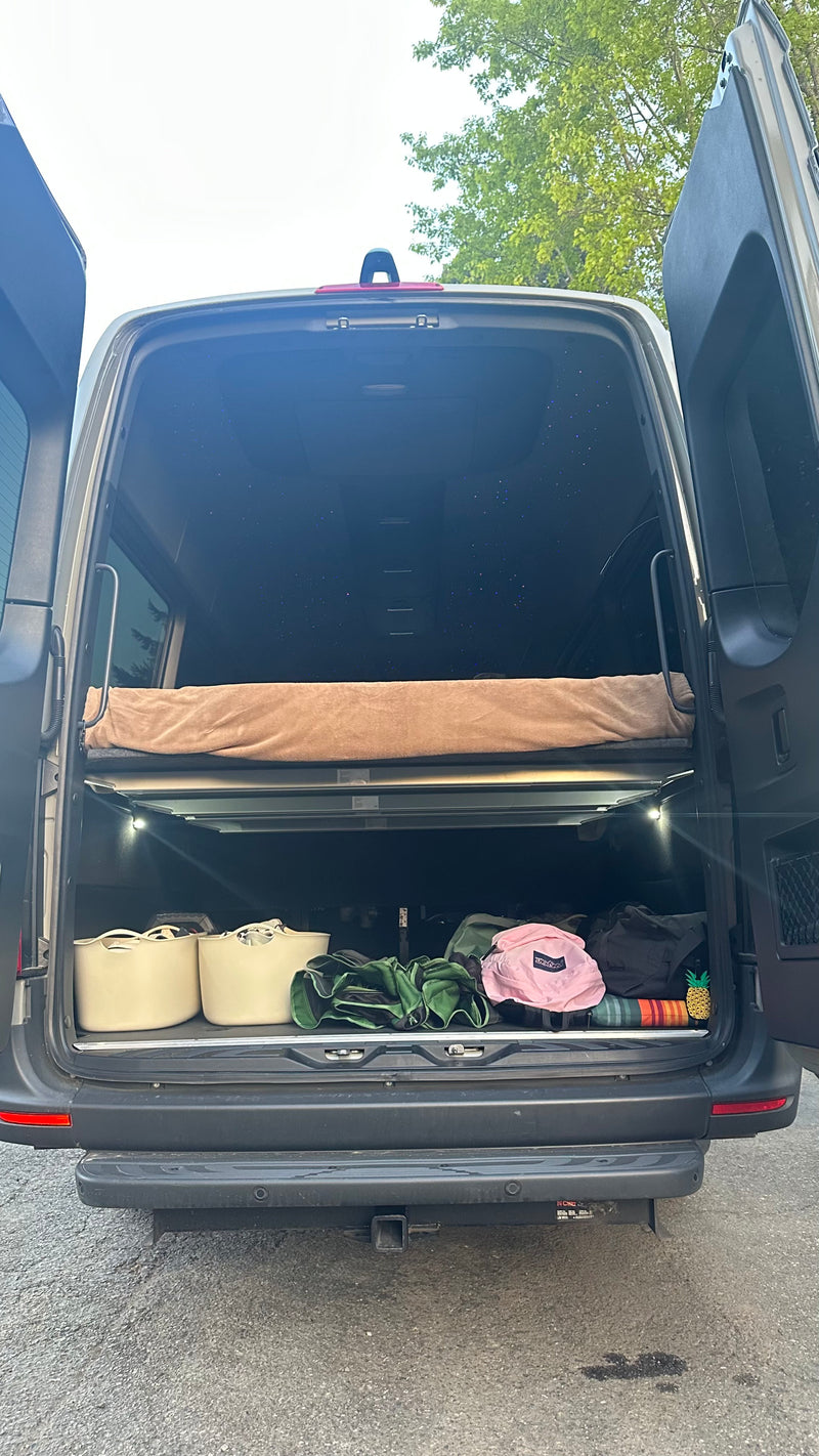 RV rental camper van's open rear reveals a raised bed, starlight headliner, and organized storage space below. — photo 7