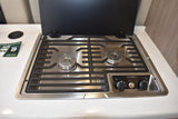 RV rental kitchen features a Dometic two-burner stovetop with grates and control knobs, lid open.