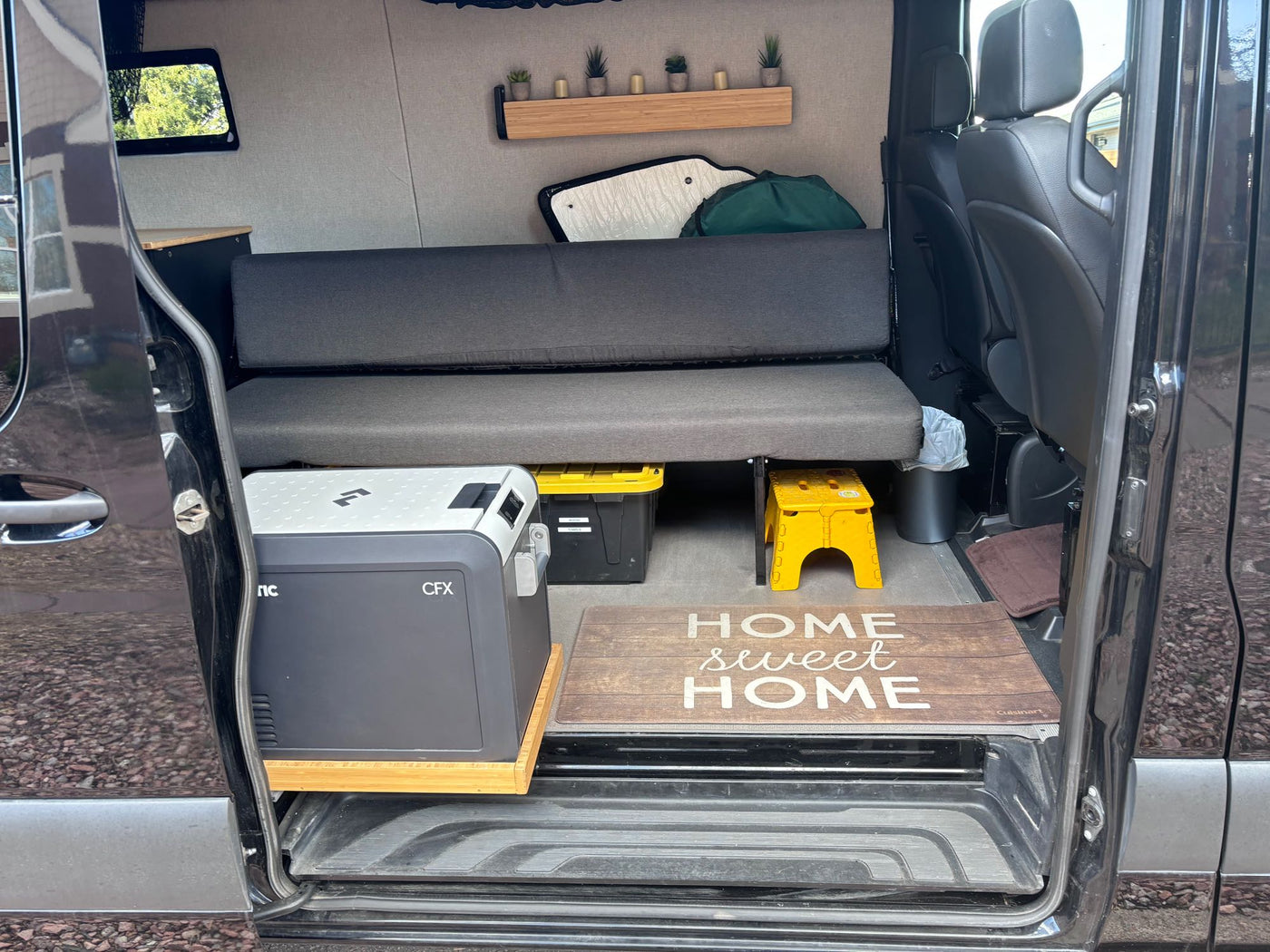  and decor shelf. Ideal for mobile van living adventures.|RV rental: Portable toilet stored on pull-out slide between custom black and wood cabinets — photo 3