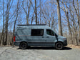 This gray Mercedes-Benz Sprinter rv rental van is parked on a gravel path
